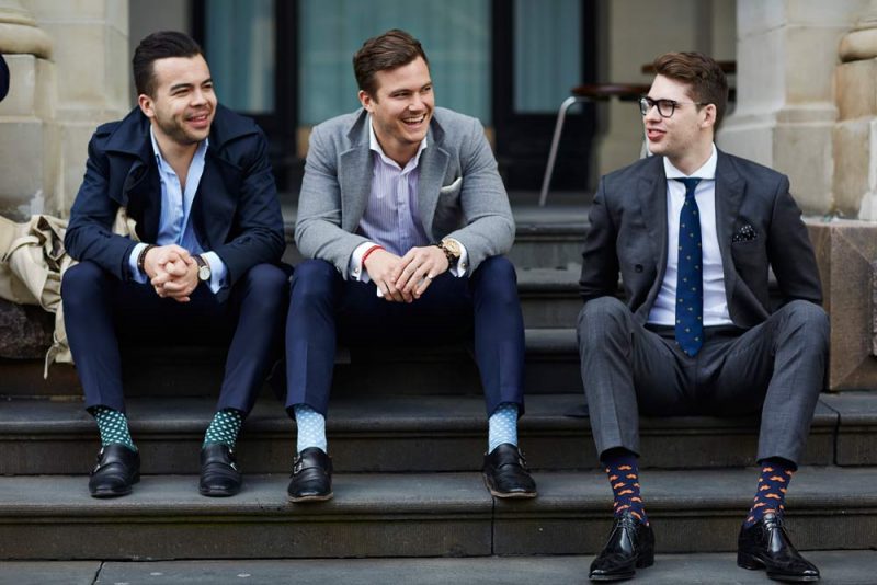 three men in blue and grey tone suits sitting on steps