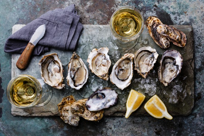 freshly shucked oysters with lemon on a board