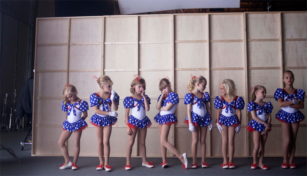 A line of blonde girls wearing matching costumes