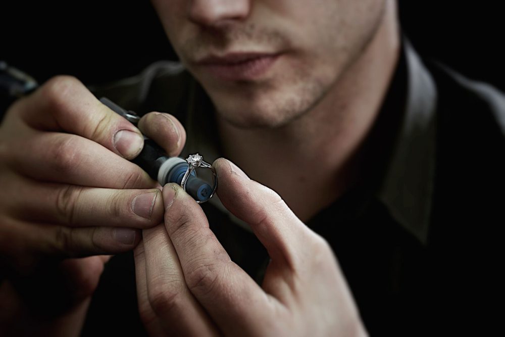 close-up of a jeweller preparing a diamond and silver engagement ring