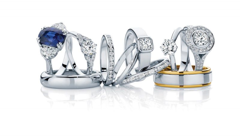 array of silver and diamond engagment rings and wedding bands with a white backdrop