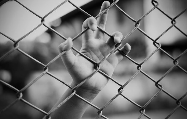 A girl's hand rests on a fence. Image: Chatiyanon