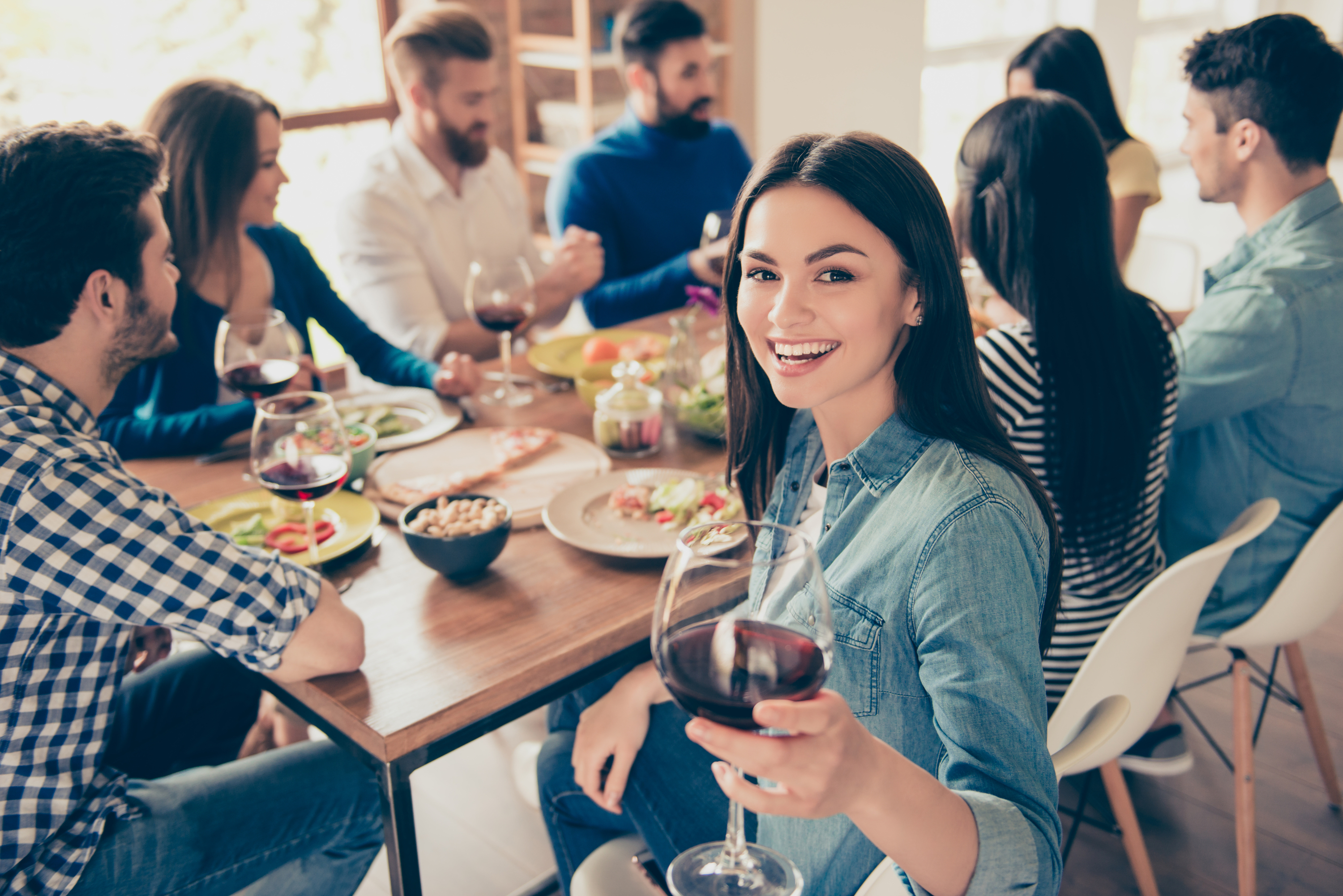 A girl holding a glass of red wine at a party with friends. Image: Roman Samborskyi