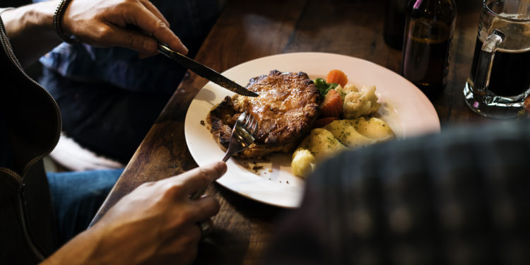 Friends eating steak. Image by rawpixel.com via Shutterstock.
