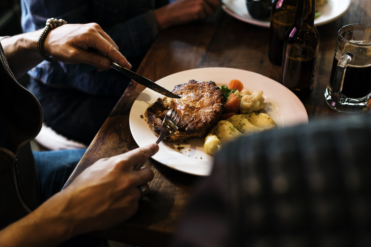 Friends eating steak. Image by rawpixel.com via Shutterstock.