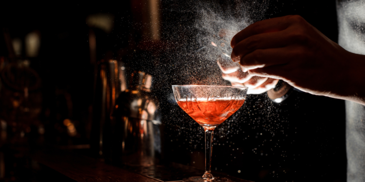 Bar sprinkling juice over cocktail. Photography by Maksym Fesenko. Image via Shutterstock.