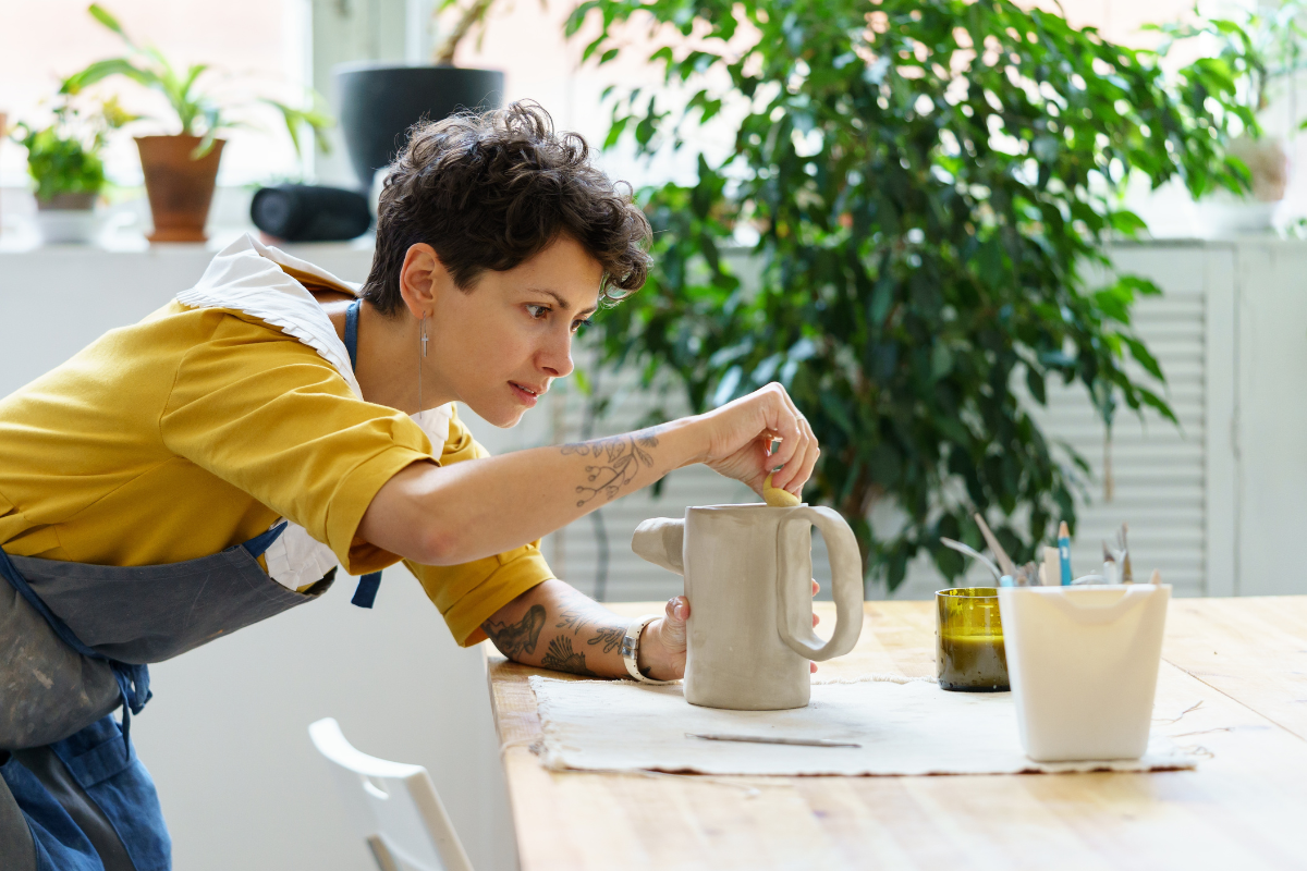 Young female artisan modelling jug from raw clay. Photography by DimaBerlin. Image via Shutterstock