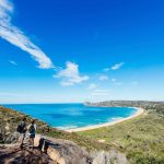 Couple enjoying a scenic coastal hike on the Barrenjoey Lighthouse Walk in Palm Beach, Sydney. Image: Destination NSW