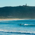 Stand up paddleboarder catches a morning wave at Palm Beach on Sydney's northern suburbs. Image supplied by Destination NSW.