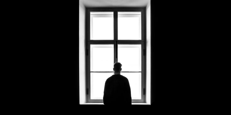 Man at window. Photographed by Sasha Freemind. Image via Unsplash