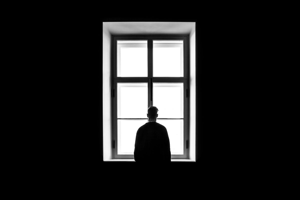 Man at window. Photographed by Sasha Freemind. Image via Unsplash