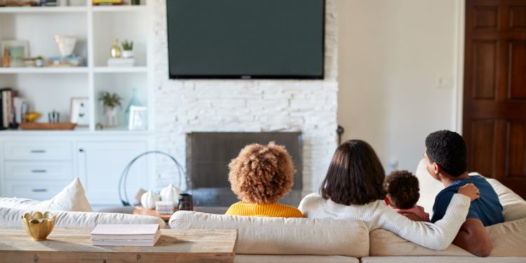 Family watching TV in nice living room seen from behind