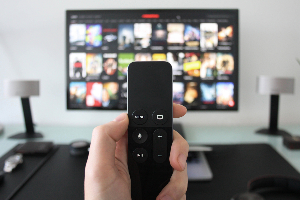 tv remote in foreground with screen with movie options out of focus in background