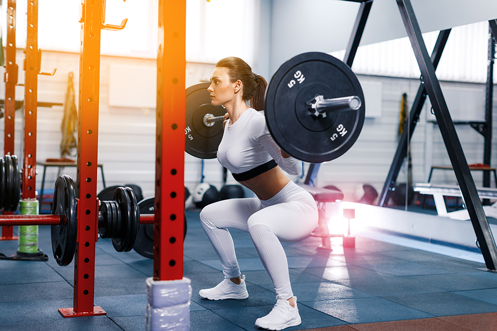 Female athlete executing weighted squats. Image purchased