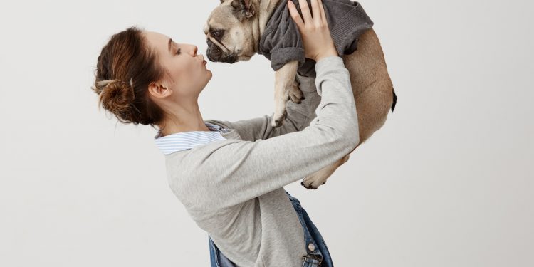 Girl holding dog. Photographed by Cookie Studio. Image via Shutterstock