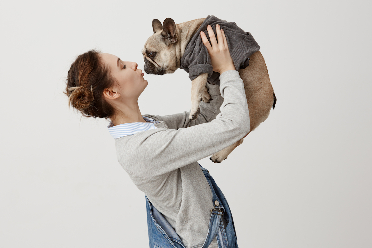 Girl holding dog. Photographed by Cookie Studio. Image via Shutterstock