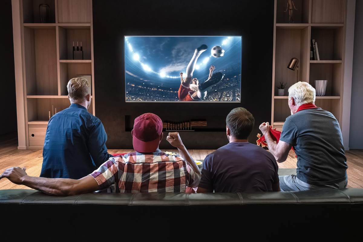 Group of fans are watching a soccer moment on the TV and celebrating a goal. Photography by Vasyl Shulga. Image via Shutterstock