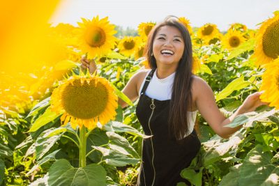 Happy woman amongst sunflowers. Photographed by Courtney Cook. Sourced via Unsplash