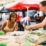 Woman buying food at farmer's market. Photographed by MinDof. Image via Shutterstock