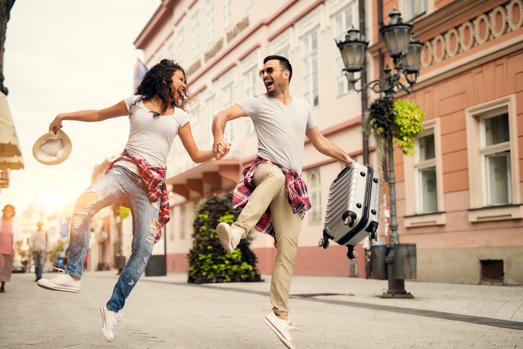 Happy couple running down the street whilst on holiday. Image via shutterstock