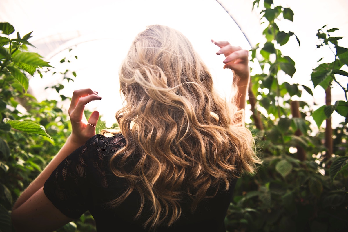 Blonde haired woman in garden. Hair. Photographed by Tim Mossholder. Image via Unsplash