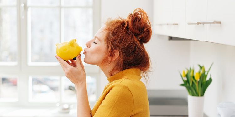 Woman holding yellow piggy bank. Image purchased via shutterstock.