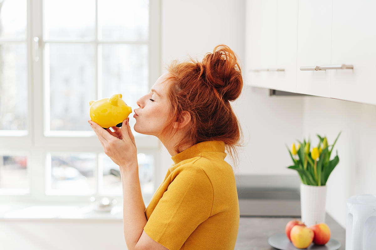 Woman holding yellow piggy bank. Image purchased via shutterstock.