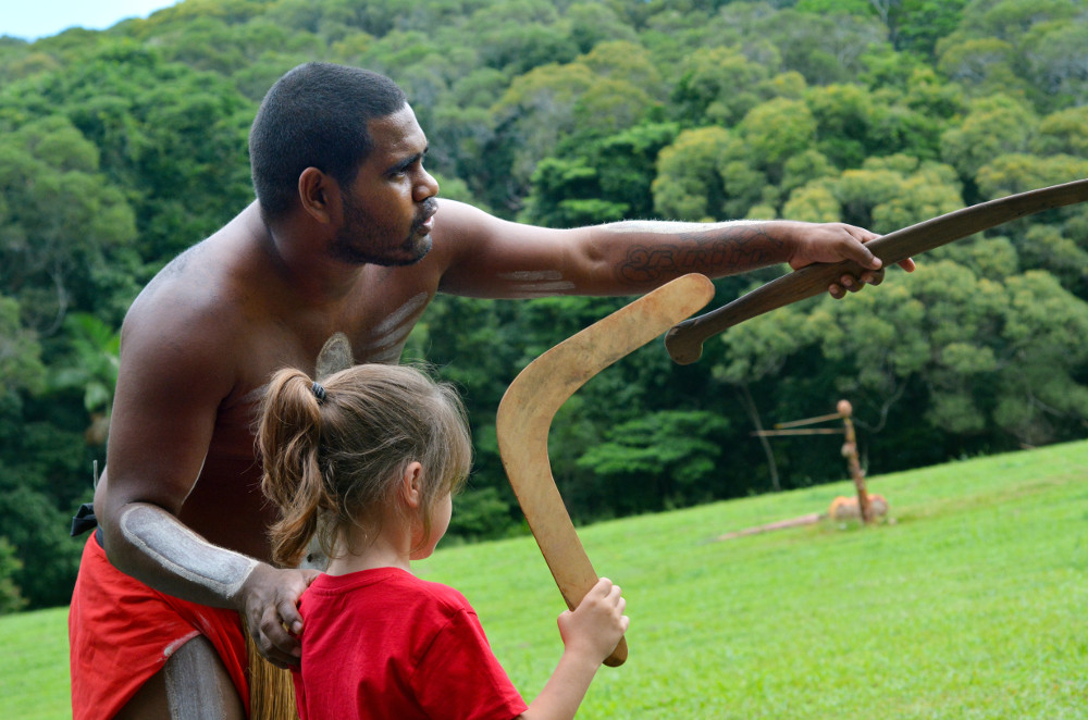 Aboriginal man showing girl how to throw a boomerang. Photographed by ChameleonsEye. Image via Shutterstock