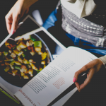 Woman holding recipe book. Photo by Dan Gold. Image via Unsplash (2)