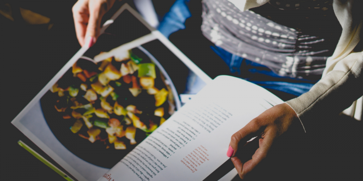 Woman holding recipe book. Photo by Dan Gold. Image via Unsplash (2)