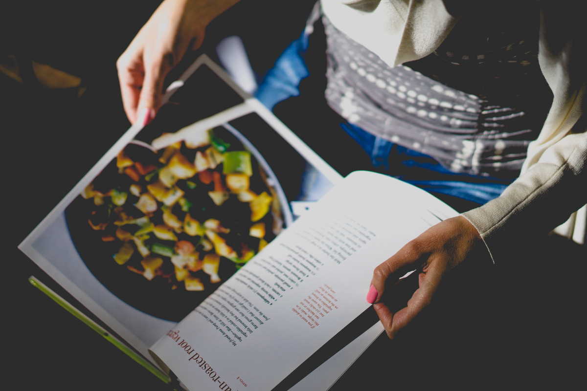 Woman holding recipe book. Photo by Dan Gold. Image via Unsplash (2)