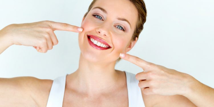 Woman smiling with teeth. Photographed by Josep Suria. Image via Shutterstock