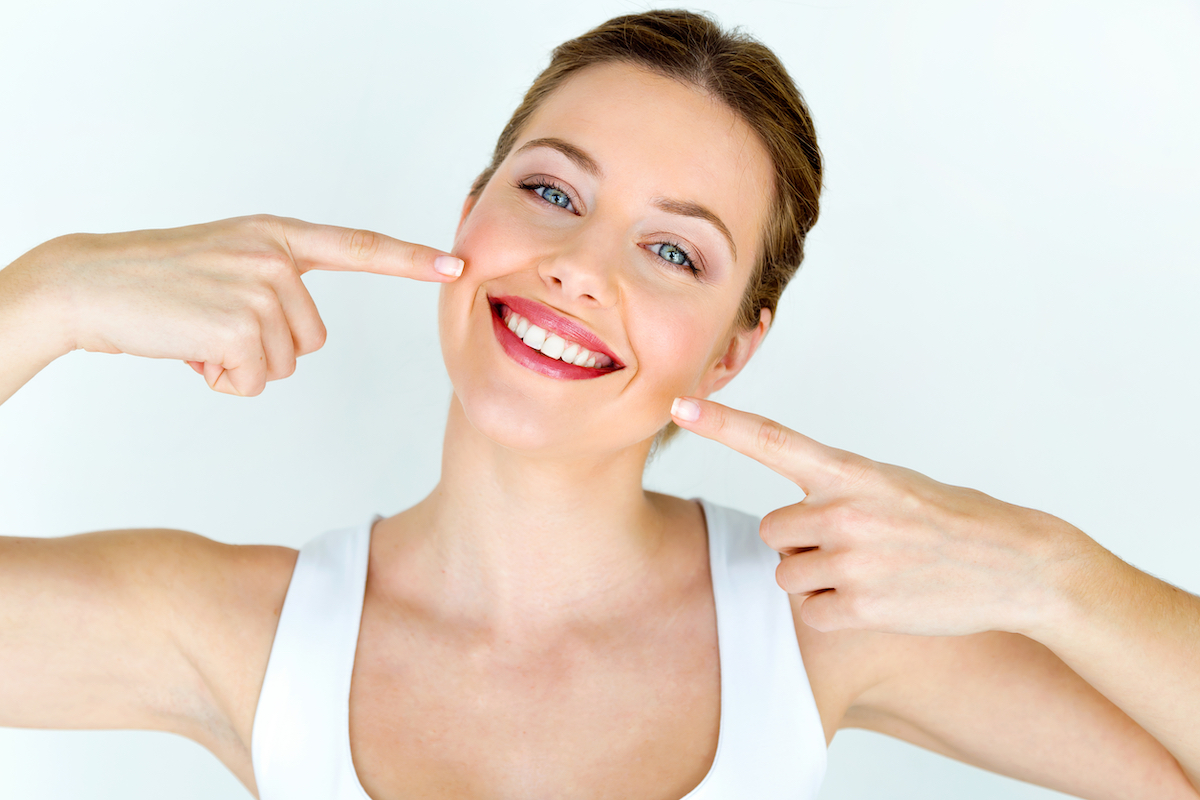 Woman smiling with teeth. Photographed by Josep Suria. Image via Shutterstock