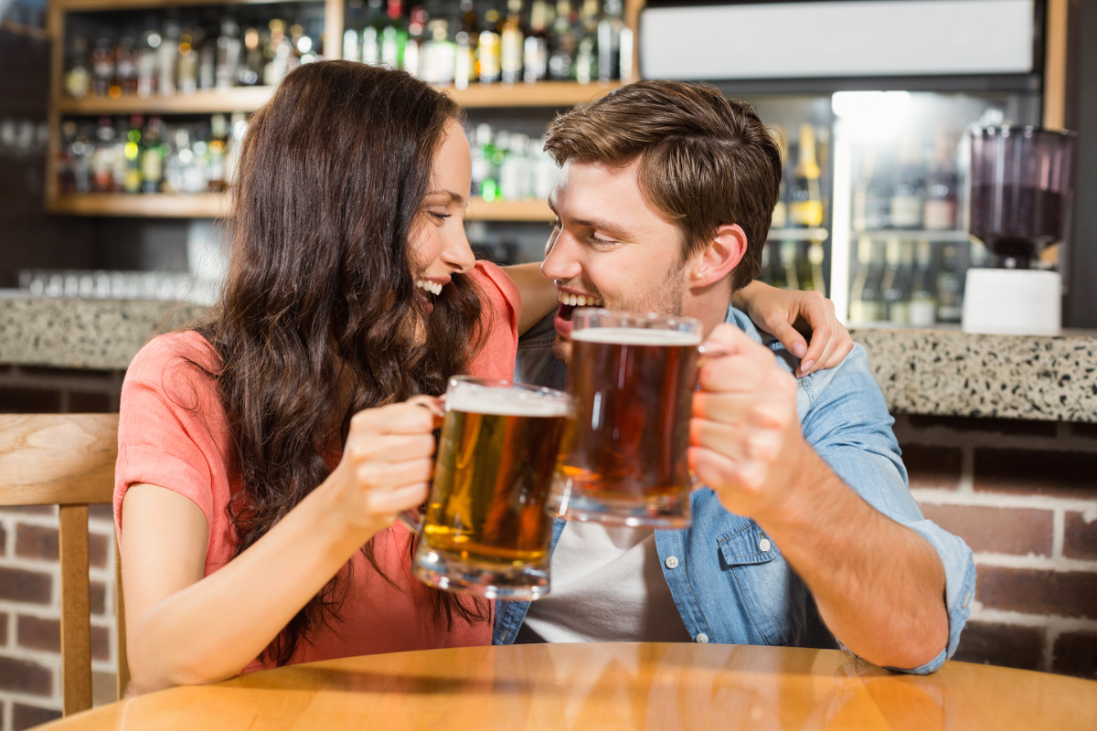 Couple drinking beer at pub. Photographed by wavebreakmedia. Image via Shutterstock