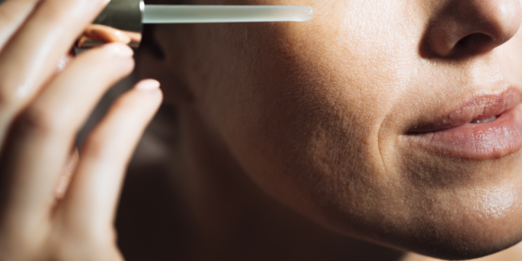 Woman applying serum to her face. Photographed by LStock Studio.