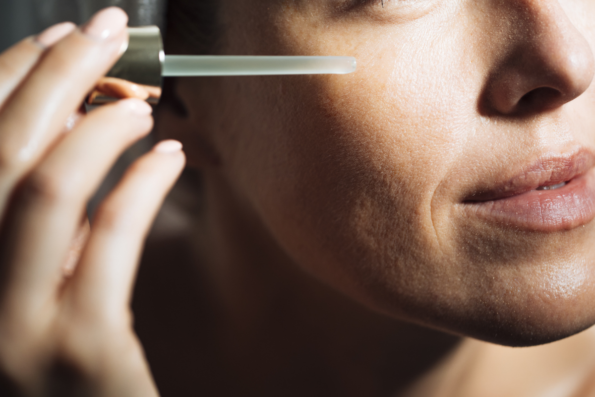 Woman applying serum to her face. Photographed by LStock Studio.