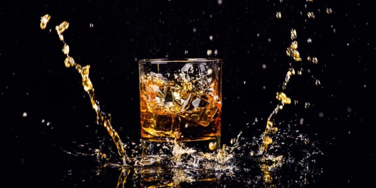 Isolated shot of whiskey with splash on black background. Photographed by The Len. Image sourced via Shutterstock.