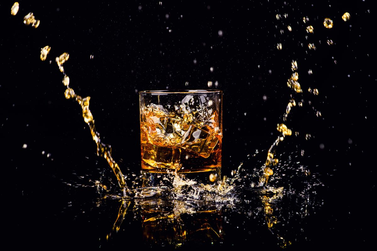 Isolated shot of whiskey with splash on black background. Photographed by The Len. Image sourced via Shutterstock.