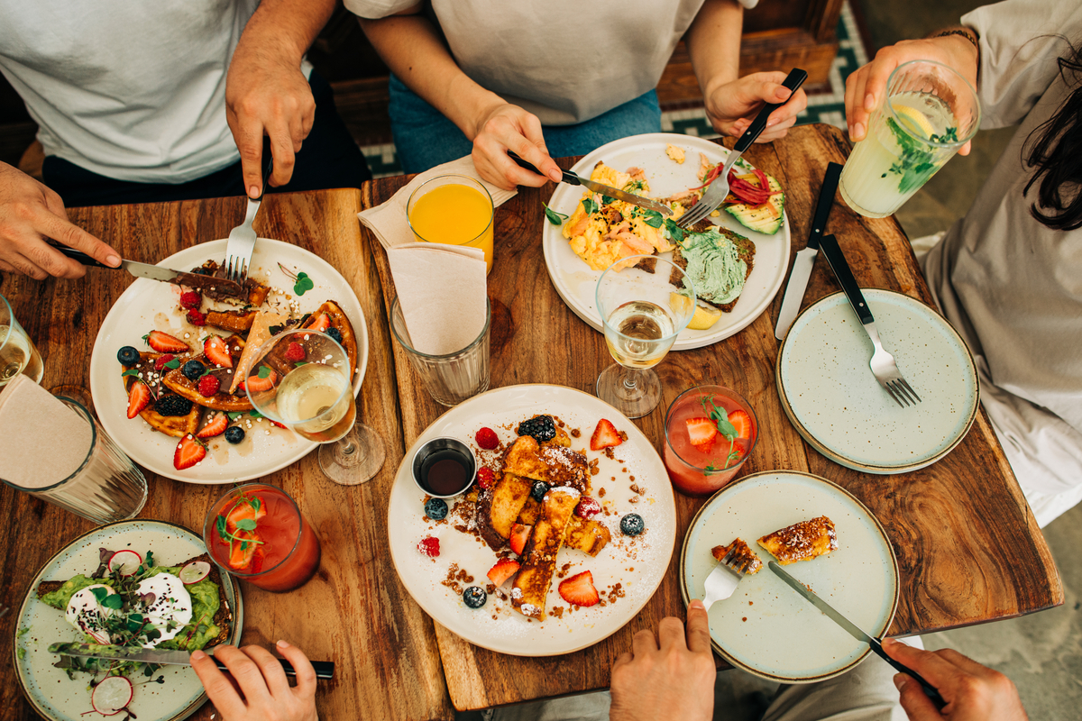 Group of friends eating breakfast or brunch in restaurant. Photographed by Cavan Images. Image sourced via Shutterstock.