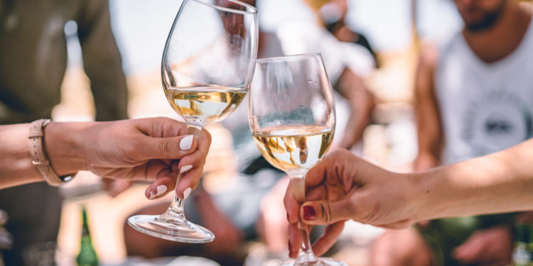 Group drinking white wine. Photographed by Zan. Image via Unsplash