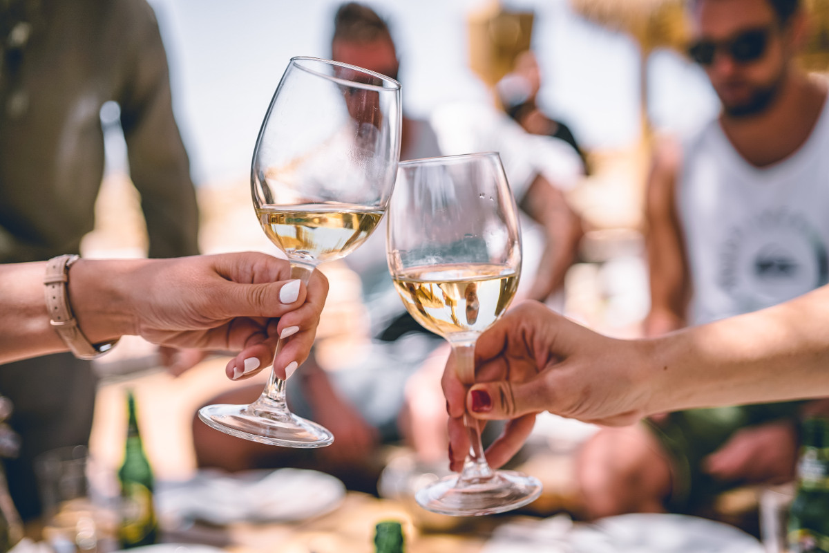 Group drinking white wine. Photographed by Zan. Image via Unsplash