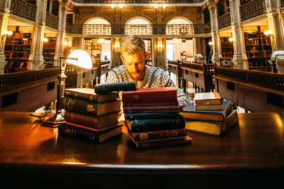 Man reading books. Photographed by Elijah Hail. Image via Unsplash