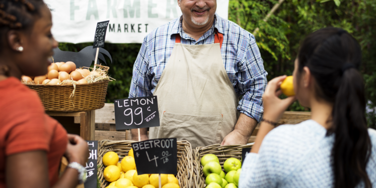 Grocer selling at farmers market. Photographed by Rawpixel. Image via Shutterstock