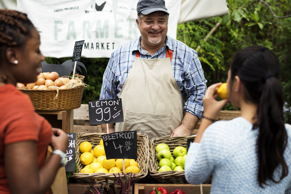 Grocer selling at farmers market. Photographed by Rawpixel. Image via Shutterstock