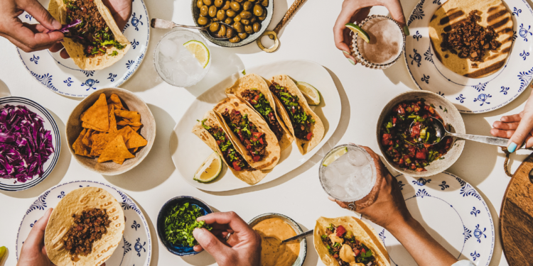 People sharing Mexican food. Photography by Foxys Forest Manufacture. Image via Shutterstock