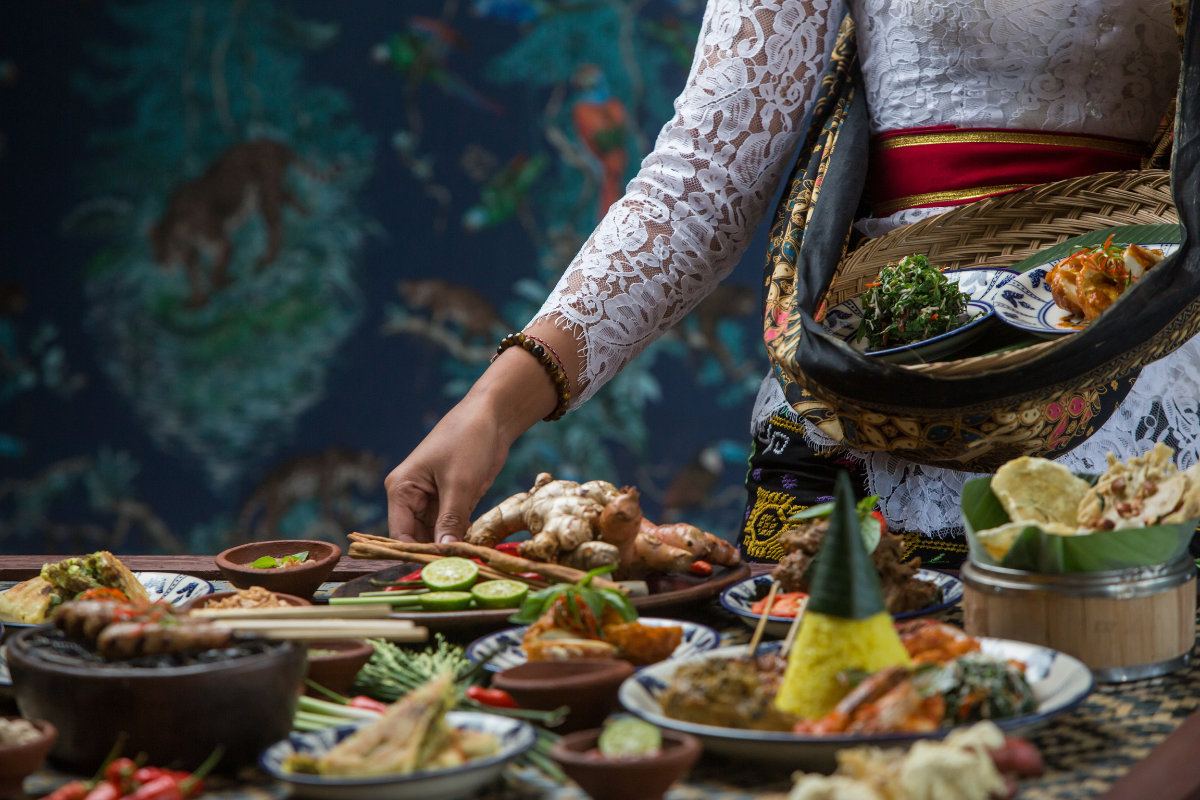 Waitress is serving traditional Balinese dishes on the table. Photography by Space_Cat. Image via Shutterstock