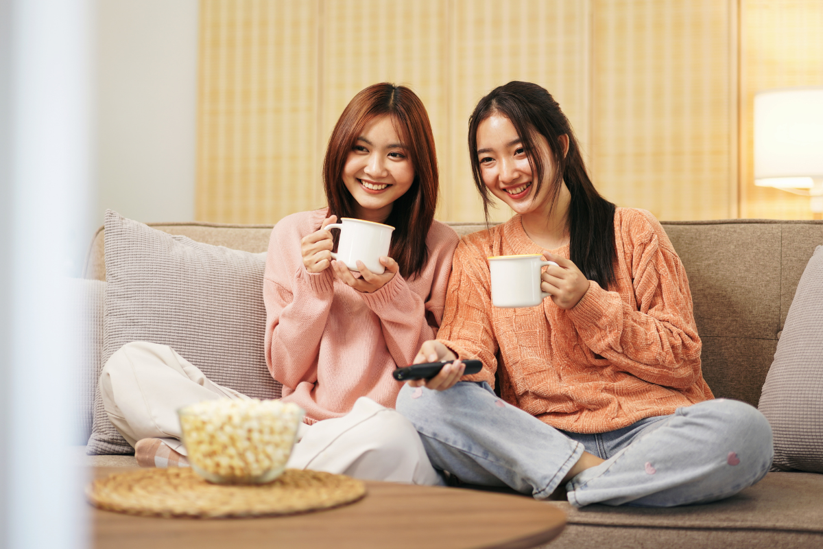 Young lesbian couple watching TV. Photography by Katcha_Natsarin. Image via Shutterstock