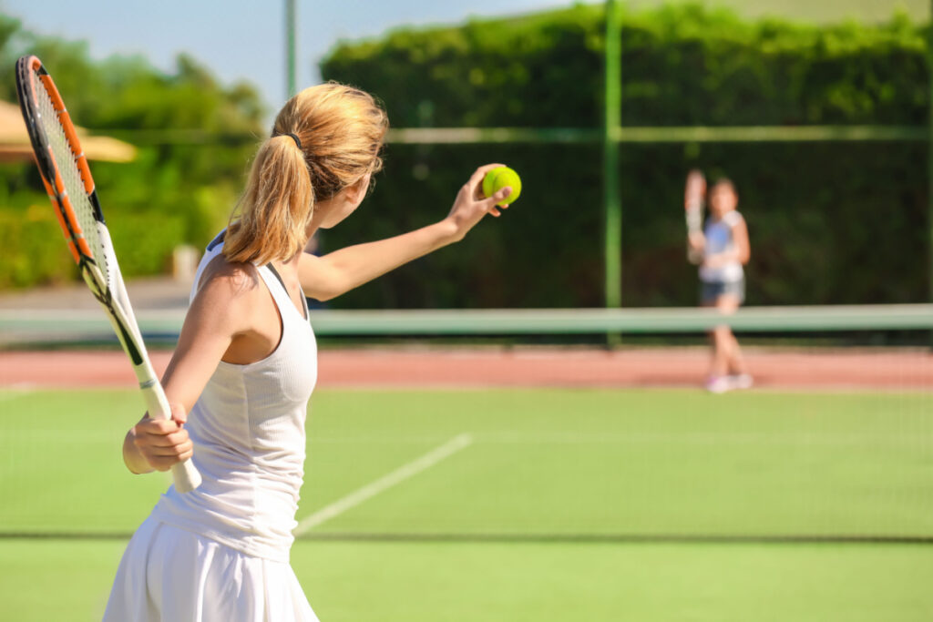 Young woman playing on tennis court. Photography by Africa Studio. Image via Shutterstock