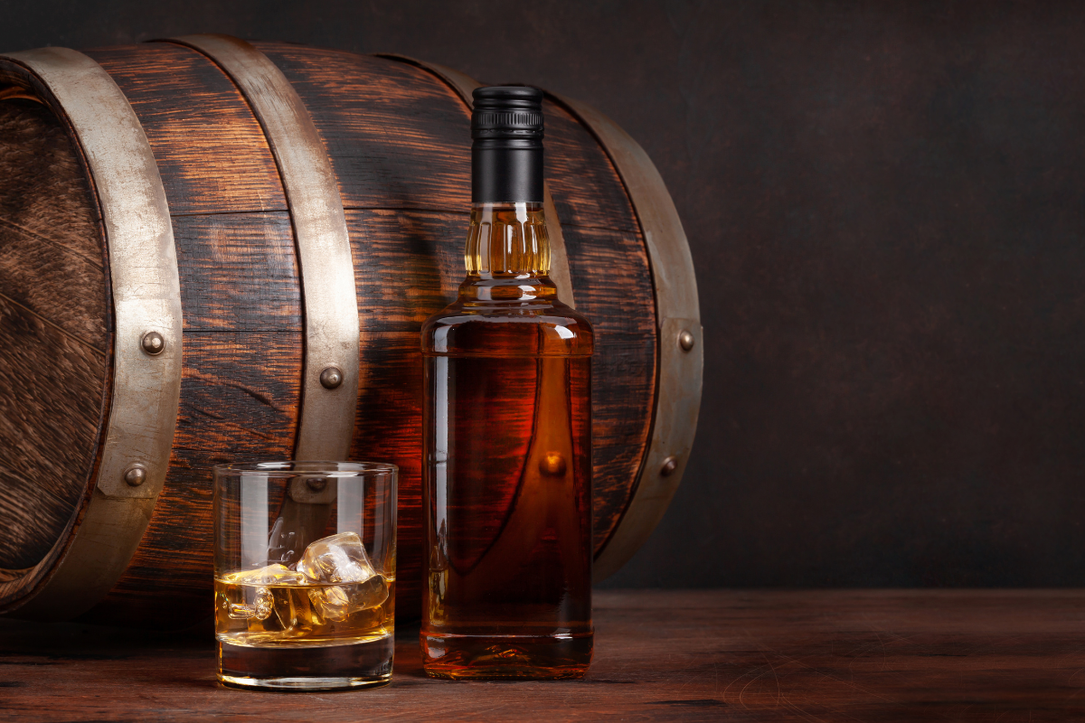 Whisky bottle and barrel. Photography by evgeeenius via Shutterstock