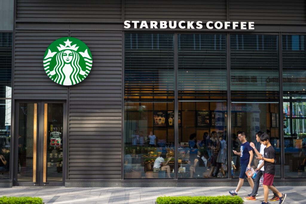 Young Chinese men walking past Starbucks, China. Image via Shutterstock